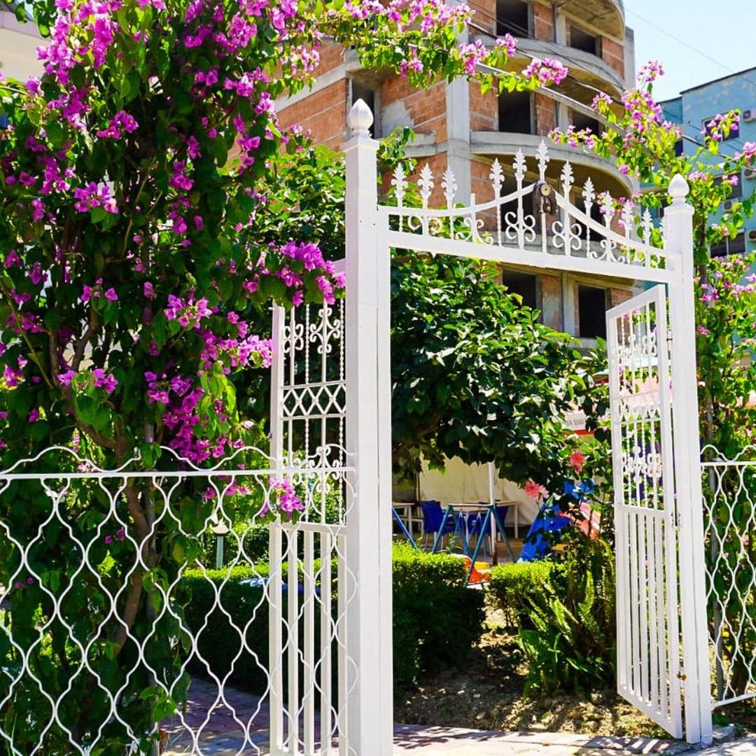 The white garden gate under pink bougainvillea