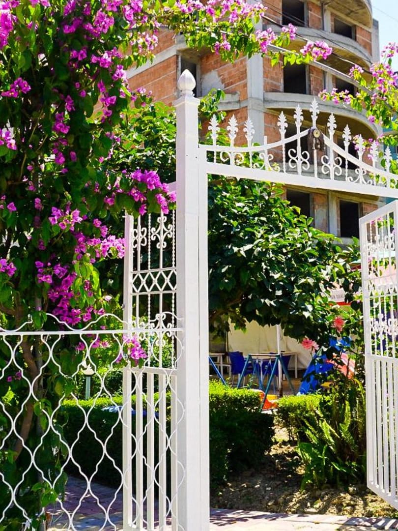 The white garden gate under pink bougainvillea